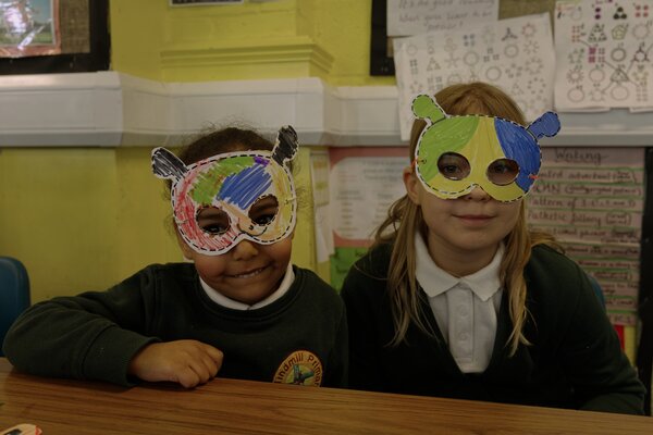 Two pupils sat at a desk wearing masks